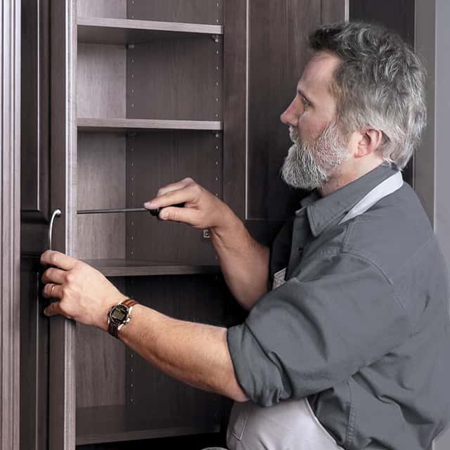 man installing cabinet shelf